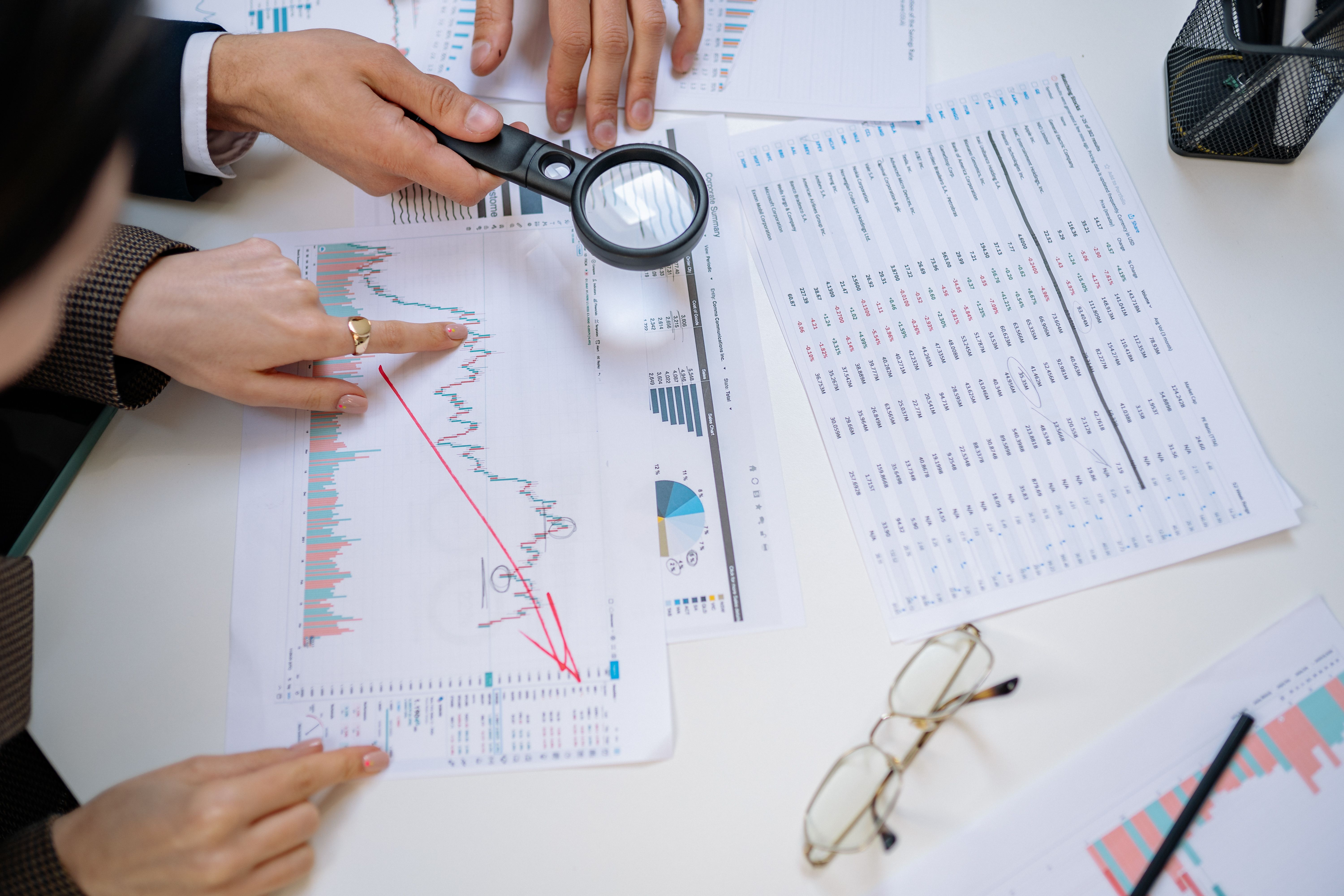 Business professionals examining financial documents with a magnifying glass
